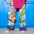 The model wears colorful trousers