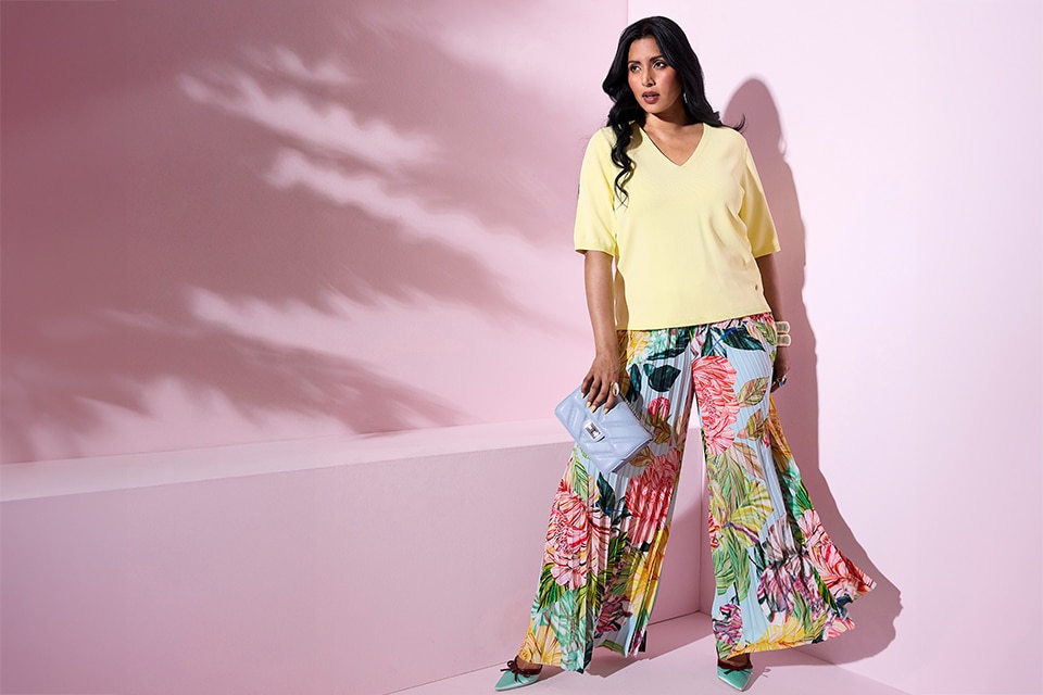 The model wears floral pants and a yellow t-shirt.