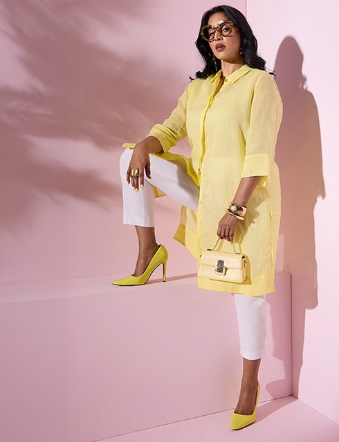 The model is wearing a  long, yellow blouse and white pants
