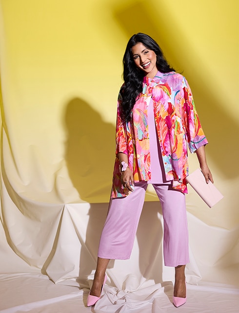 The model is wearing a colorful blouse with a pink shirt and pants.
