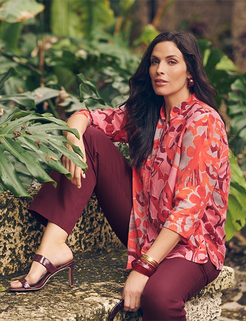 The model is wearing a colorful blouse with a red pants.
