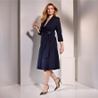 The model is wearing a blue dress with a bow.