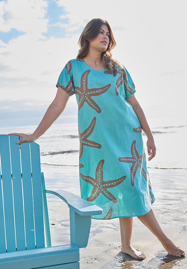 Model posiert mit einem blauen Kleid und steht im Wasser