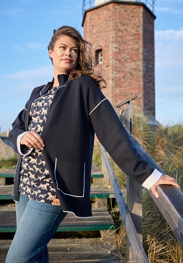 Model trägt eine Jeansjacke und sitzt auf einem Felsen