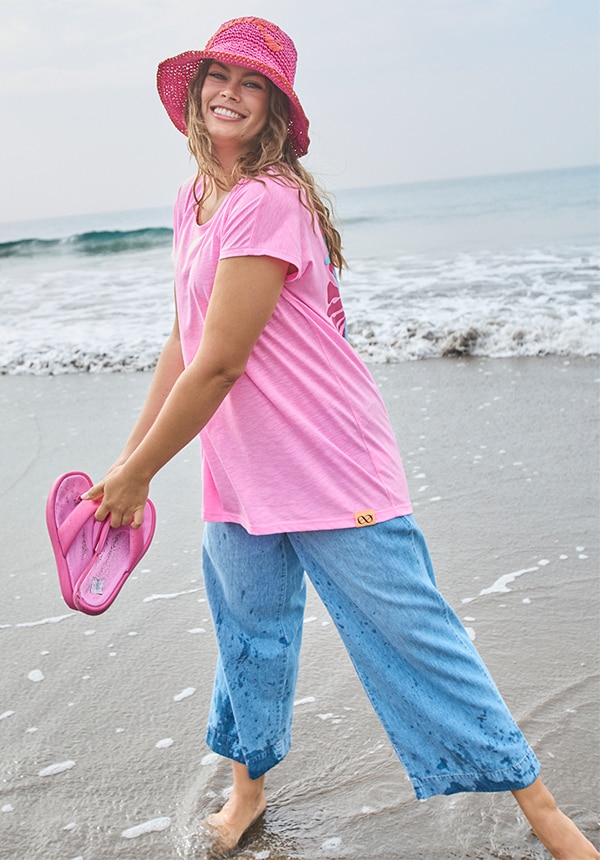 Model trägt eine Jeansjacke und sitzt auf einem Felsen