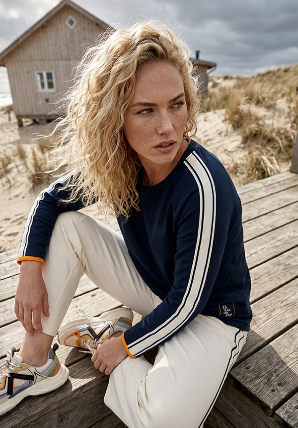 Model trägt ein shirt und eine luftige Hose und steht im Wasser