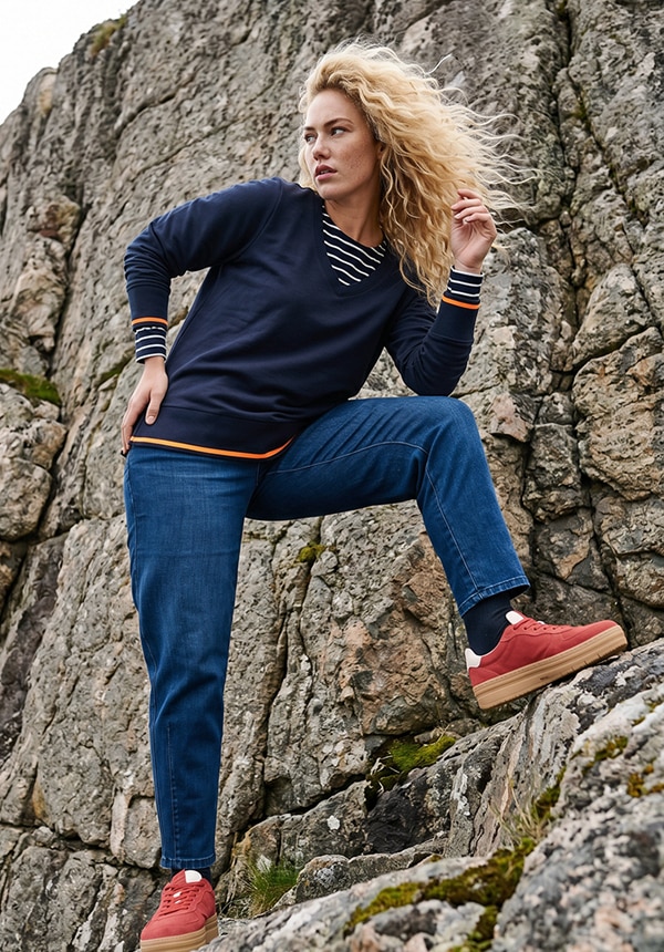 Model trägt ein grün gestreiftes Shirt und eine Jeans.