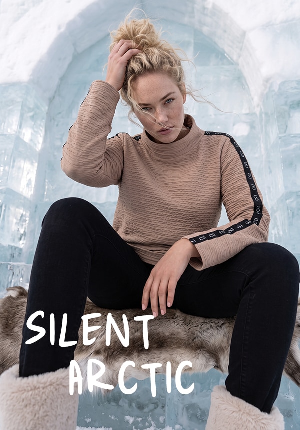 Model trägt ein grün gestreiftes Shirt und eine Jeans.