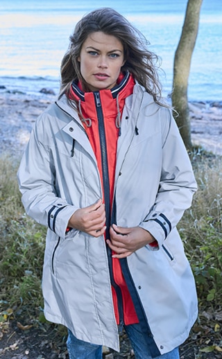 Frau mit heller Jacke am Strand