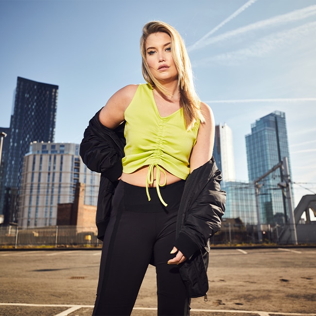 The model wears a neon yellow top with a black oversized bomber jacket.