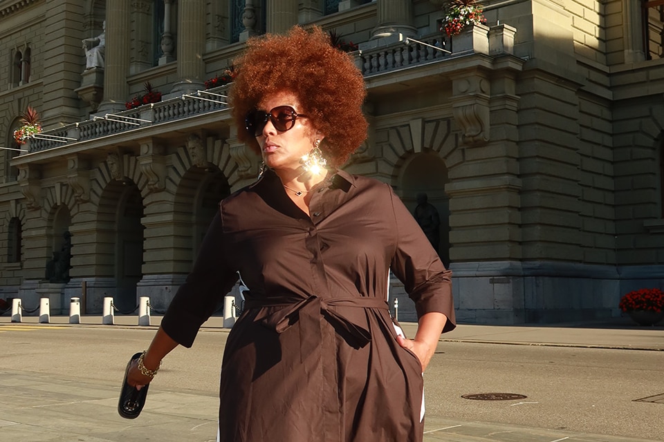 The model wears a brown dress and sunglasses