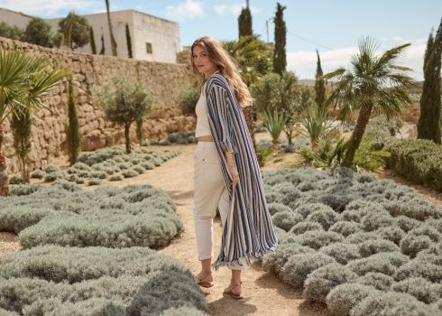 The model is posing with a blue striped knit cardigan