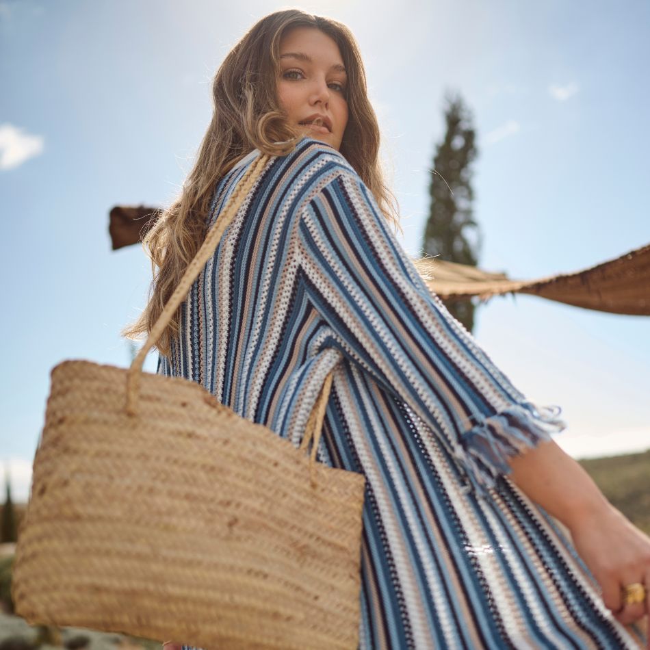 The model is posing with a blue striped knit cardigan