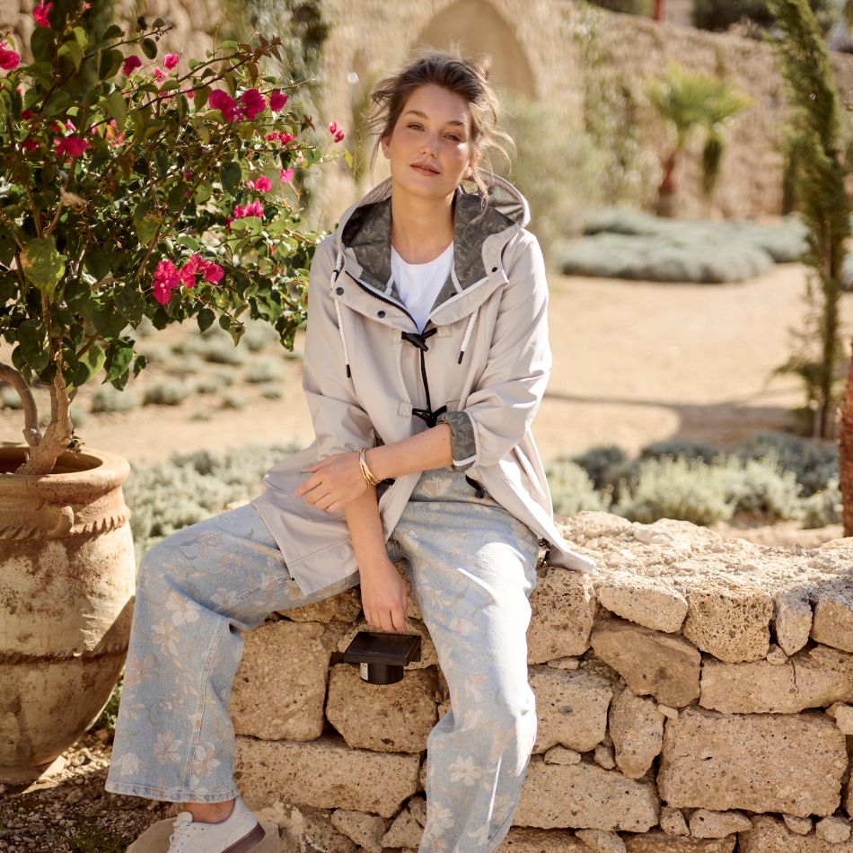 The model is posing with a beige Hyprar jacket