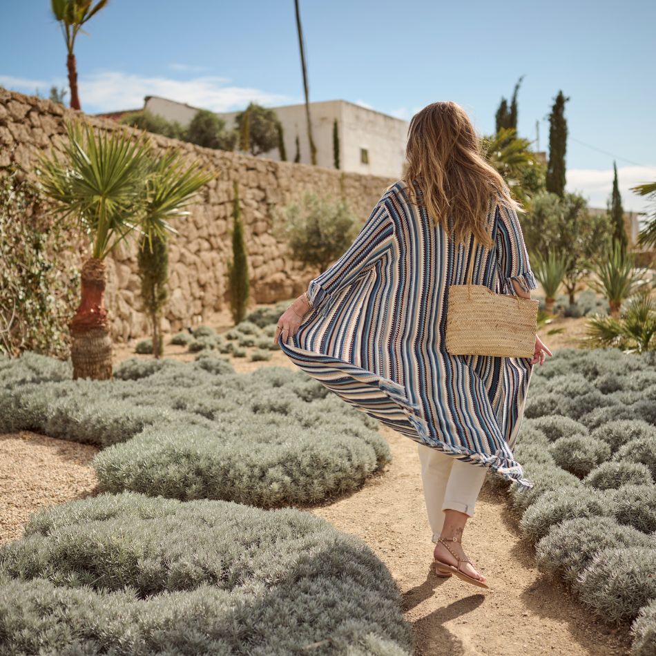 The model is posing with a blue striped knit cardigan