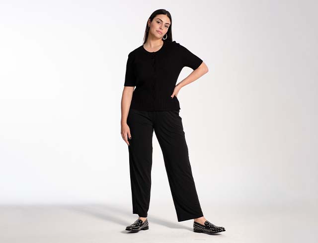 Model wears a black knit shirt and black pants
