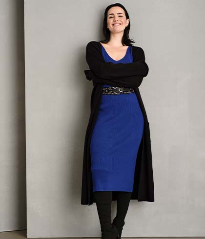 The model wears a long blue ribbed dress