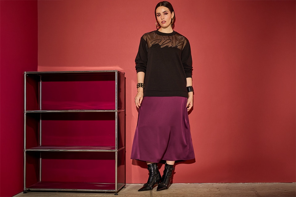 The model poses in a black skirt and a red skirt