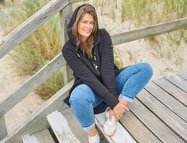 The model wears a beige sweatshirt