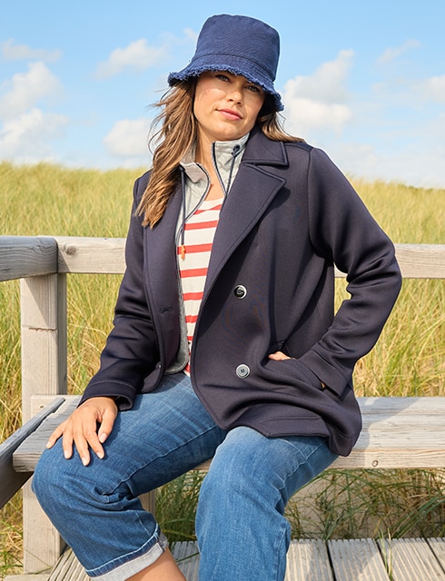 The model is wearing a blue loden jacket, striped shirt, and jeans.
