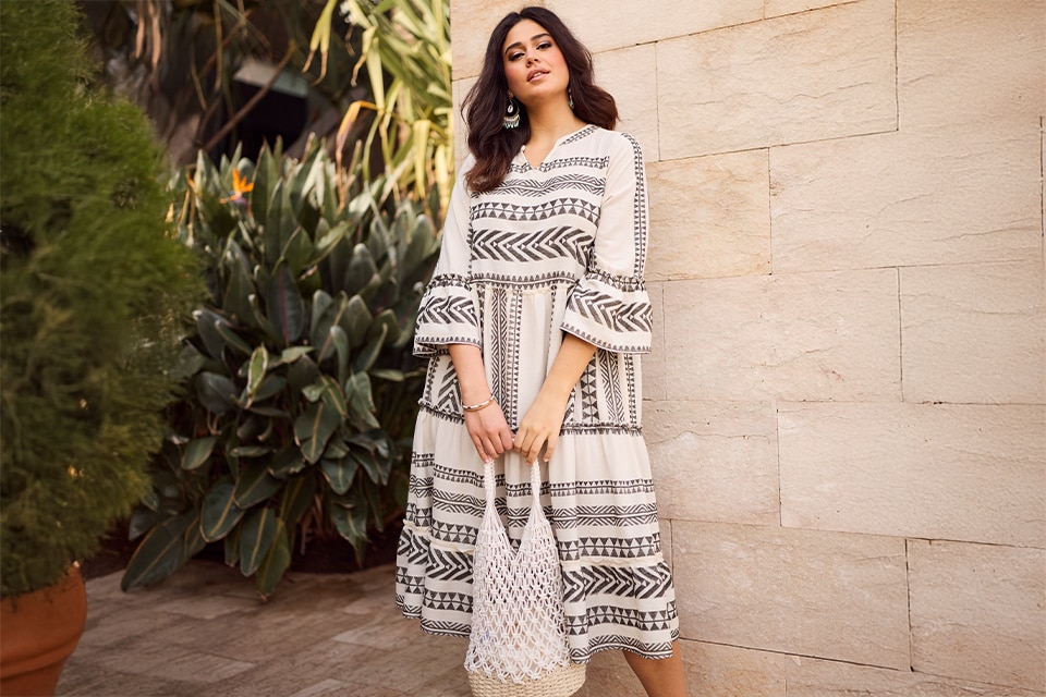 The model is wearing a white dress with black patterns

