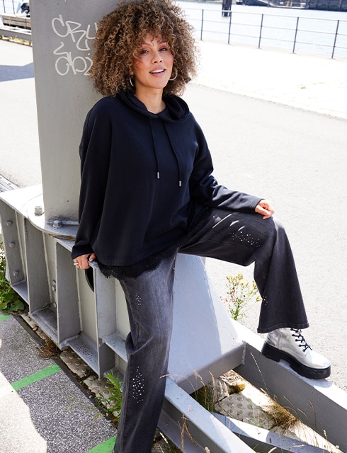 The model is waring a black Hoodie and a grey Jeans with silver Boots