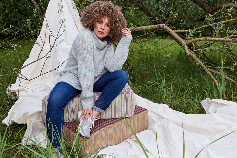 The model is wearing a grey sweater with a long Vest