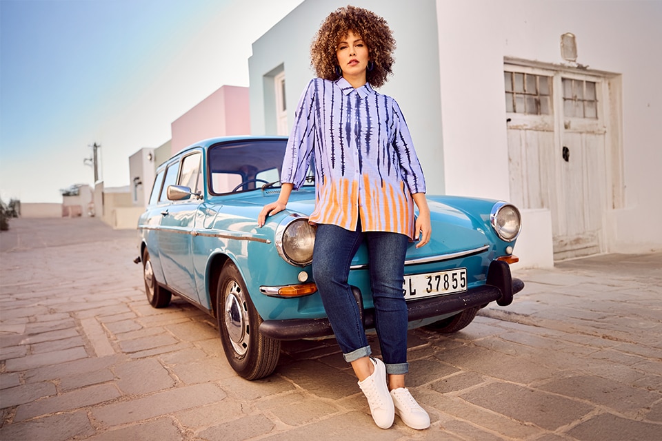 The model is wearing a white blouse and jeans.