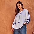 The model is wearing a white blouse with navy details.