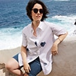 The model is wearing a white blouse with navy details.