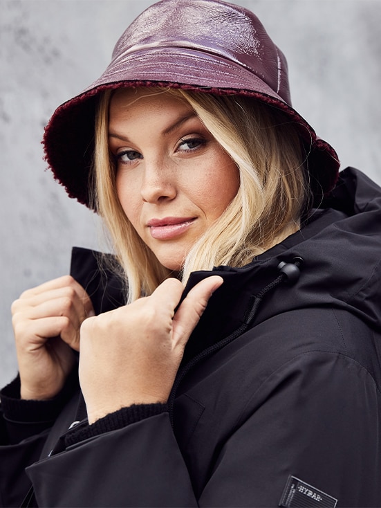Close-up of a blond woman wearing a black jacket and a red hat