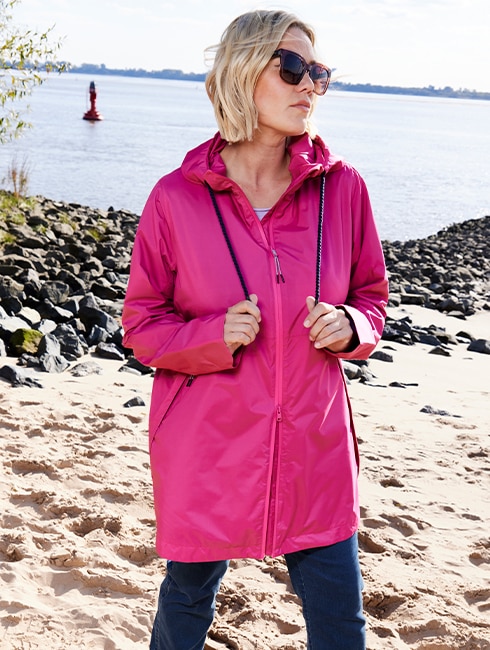 The model is wearing a pink functional rain jacket.