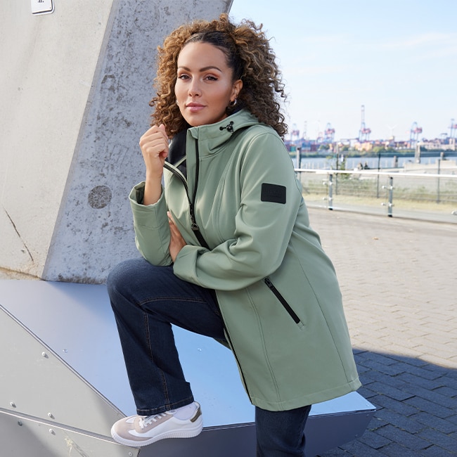 The model is wearing a pastel green softshell jacket.