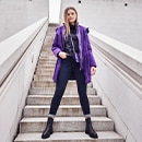 The model poses in a purple functional jacket 
