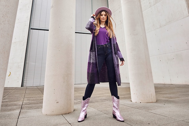 The model poses in a long, shimmering quilted coat with a matching hat 