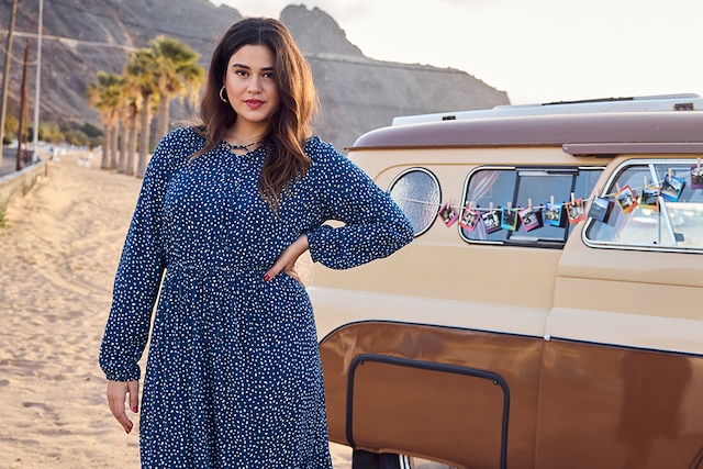 The model poses in a skirt and a purple cardigan