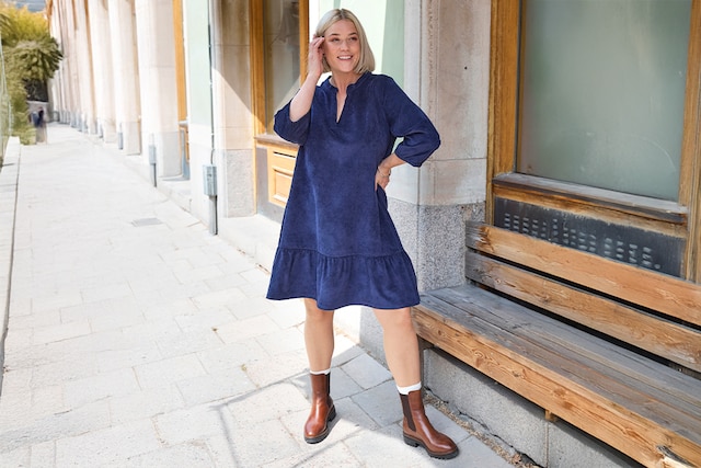 The model wears a dress and a coat