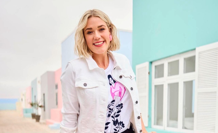 The model wears a white jacket and is sitting on a bike