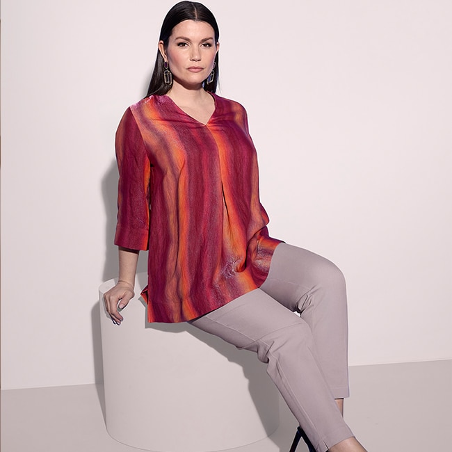 the model is wearing a colorful blouse and a red skirt.