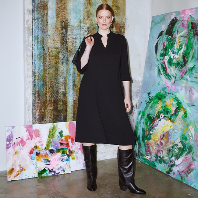 The model poses in a black knee-length dress