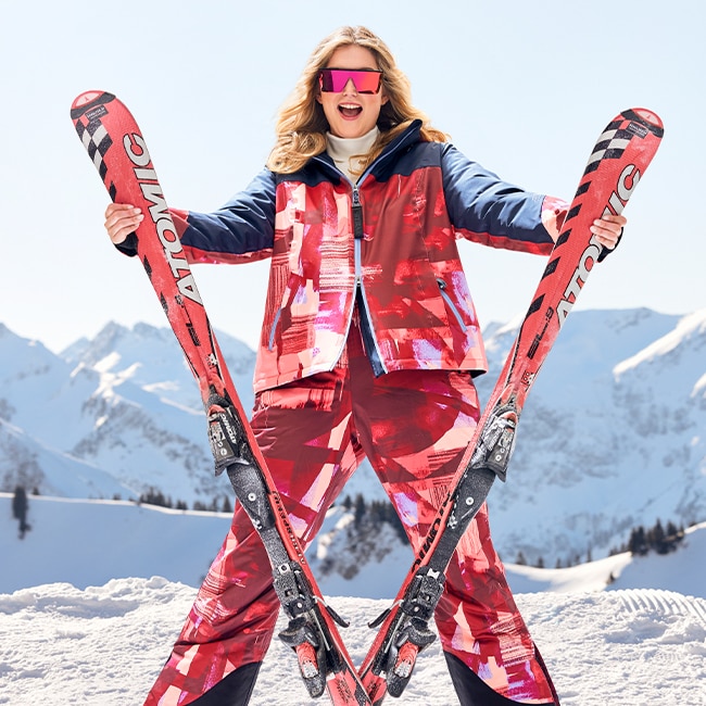 The model poses in a red snowsuit