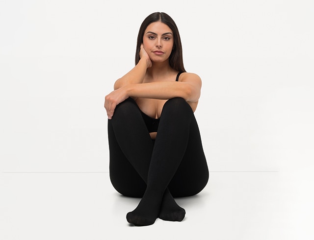 The model poses sitting in black non-see-through tights thermal function