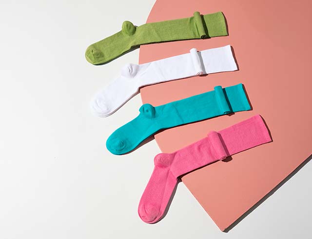 Knee-high socks in green, white, turquoise, and pink, displayed in a flat lay arrangement.