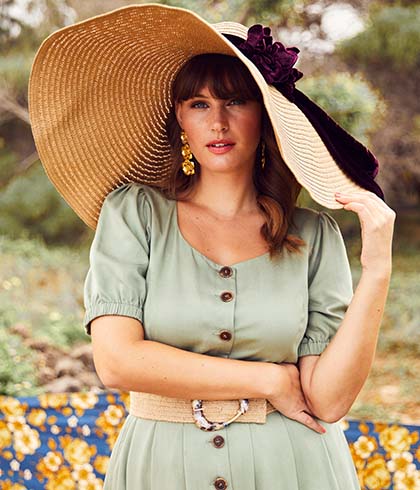 Close-up from model with green dress and big hat