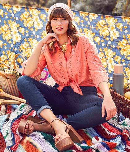 Model with blouse and headscarf sits on a picnic blanket