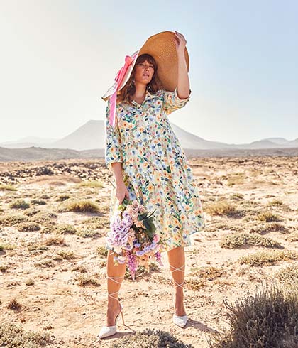 The model poses in a dress and a big sun hat 