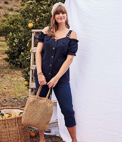 The model wears a traditional dress while posing  with a bag in her hands