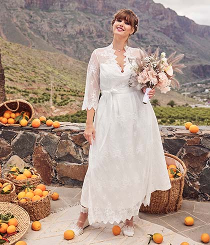 The model poses in front of the mountains while she wears a bride dress