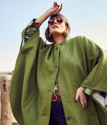 The model poses in a green cape 