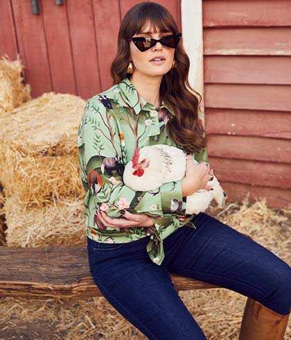 The model poses in a blue jacket and a blue cardigan with a horse
